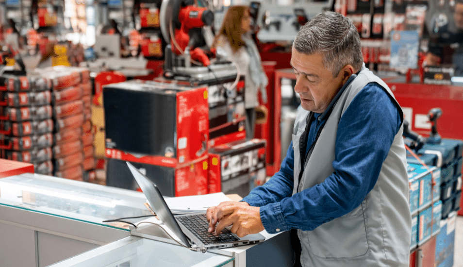 Business manager working at a hardware store and making a call while using a computer.