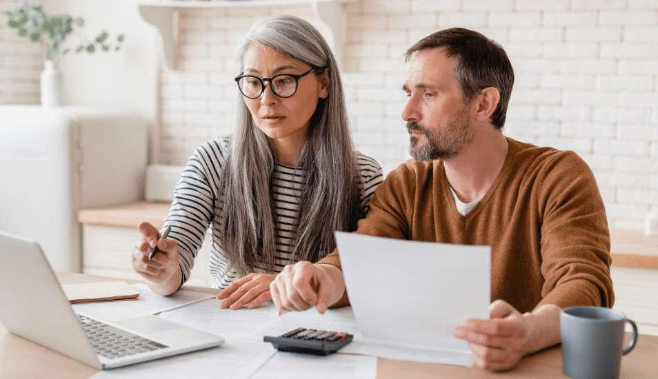 Mature middle-aged couple family wife and husband counting funds, savings declarations, investments, paperwork, financial documents, bankruptcy, court case, bills, pension with laptop.