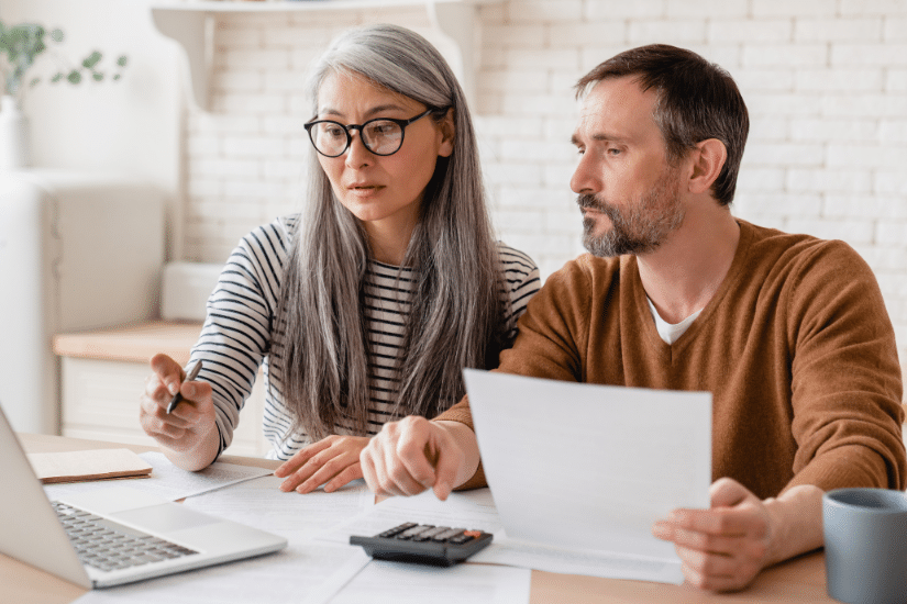 Mature middle-aged couple family wife and husband counting funds, savings declarations, investments, paperwork, financial documents, bankruptcy, court case, bills, pension with laptop.