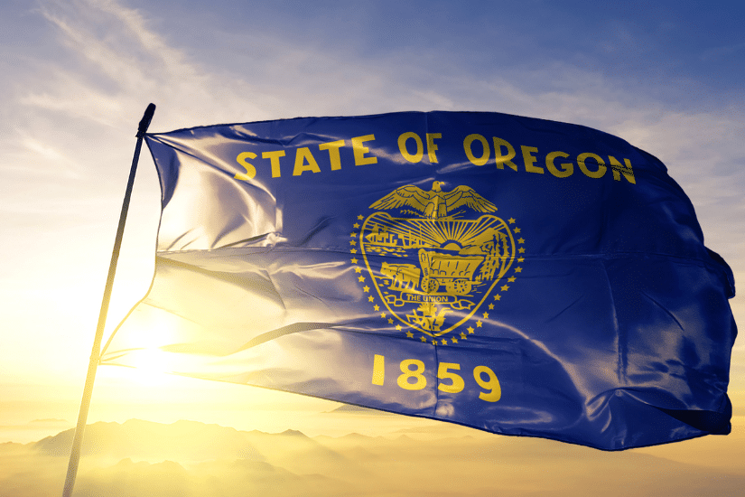 Oregon state of United States flag textile cloth fabric waving on the top sunrise mist fog.