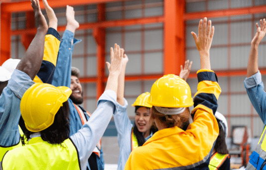 Group of workers raising hands at manufacturing industrial factory.