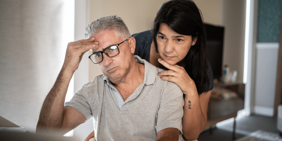 An older couple couple looking anxious while reading a computer screen