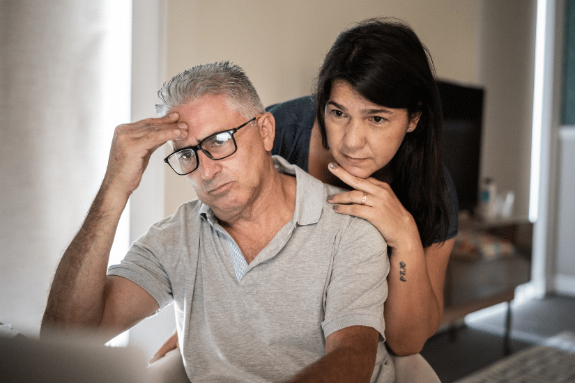 An older couple couple looking anxious while reading a computer screen