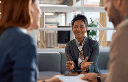 Happy black financial consultant having a meeting with her clients in the office.