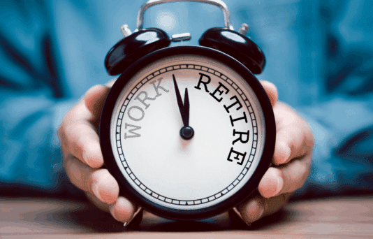 Businessman holding black alarm clock with clockwise countdown from work to retirement.