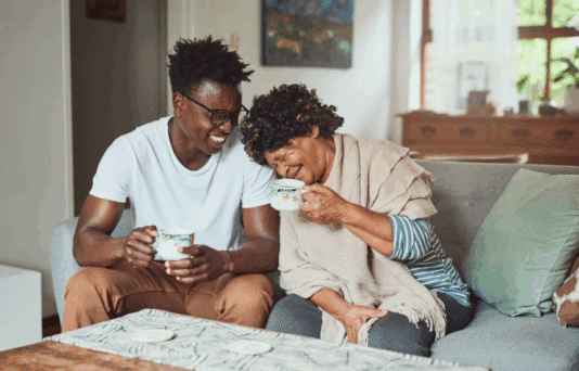 A grandmother and her grandson enjoying a cup of coffee together at home.