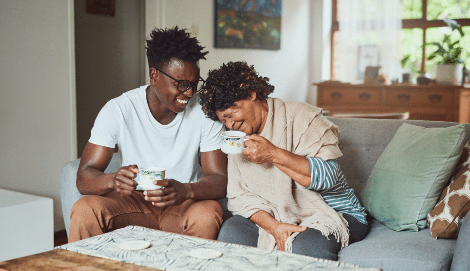 A grandmother and her grandson enjoying a cup of coffee together at home.