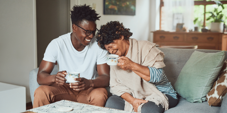 A grandmother and her grandson enjoying a cup of coffee together at home.