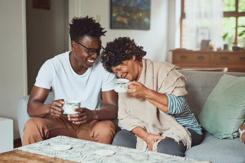 A grandmother and her grandson enjoying a cup of coffee together at home.