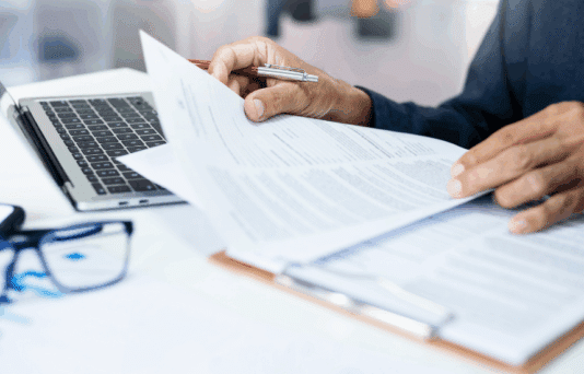 Businessman reviewing document reports at office workplace with computer laptop. legal expert, professional lawyer reading and checking financial documents or insurance contract.