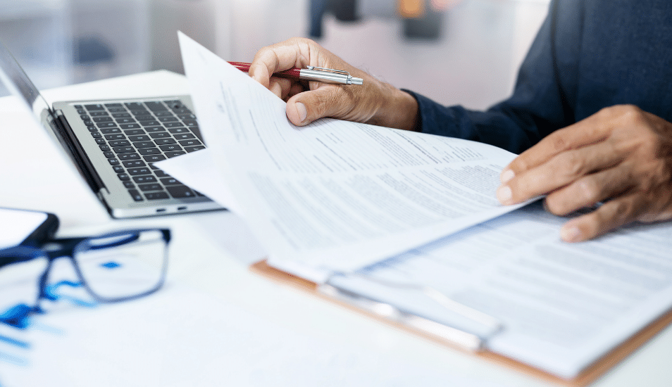 Businessman reviewing document reports at office workplace with computer laptop. legal expert, professional lawyer reading and checking financial documents or insurance contract.