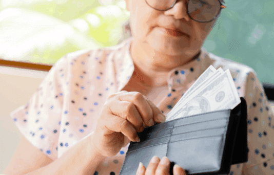 Older woman putting money into her wallet.