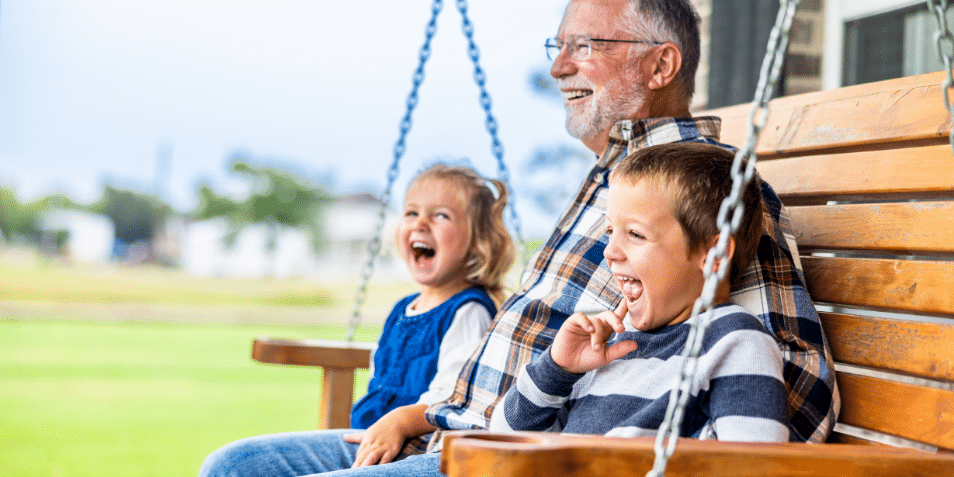 Grandpa sitting on a swing with his grandchildren.