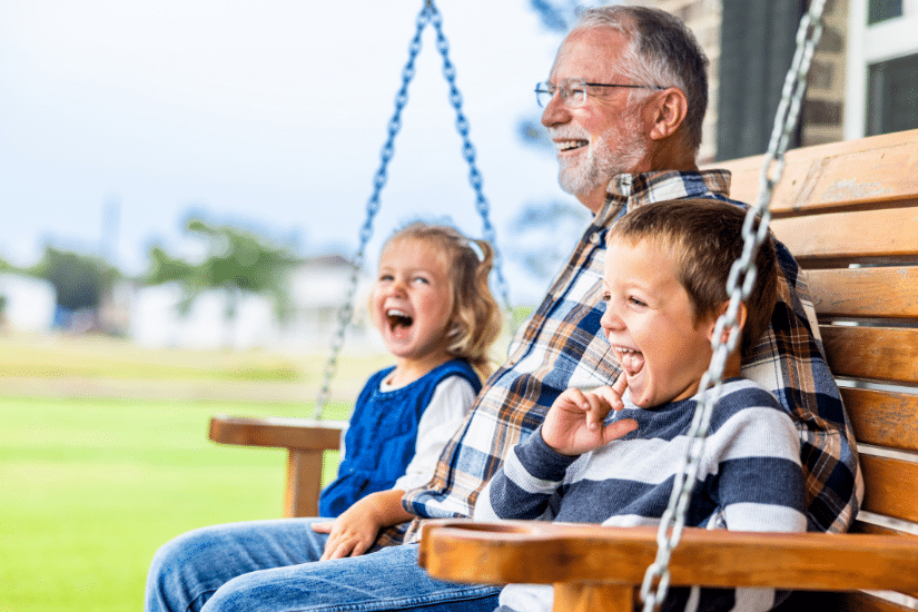 Grandpa sitting on a swing with his grandchildren.