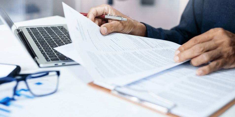 Businessman reviewing document reports at office workplace with computer laptop. legal expert, professional lawyer reading and checking financial documents or insurance contract.
