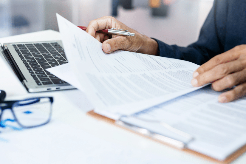 Businessman reviewing document reports at office workplace with computer laptop. legal expert, professional lawyer reading and checking financial documents or insurance contract.
