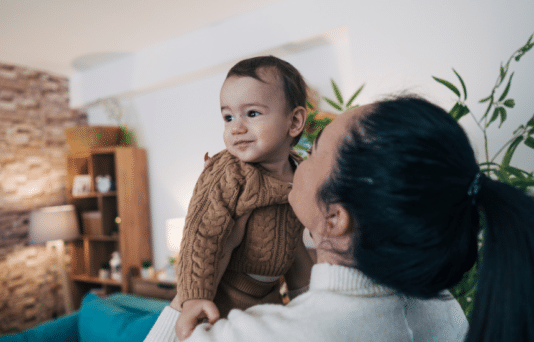 Mother holding her baby in the living room.