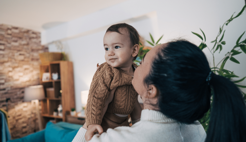 Mother holding her baby in the living room.