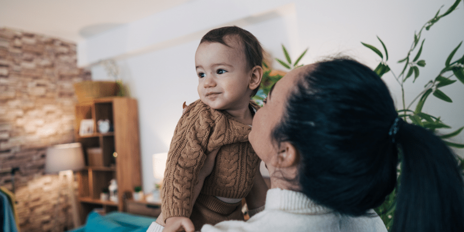 Mother holding her baby in the living room.
