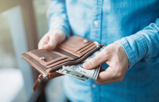 A person pulling out cash from their wallet.
